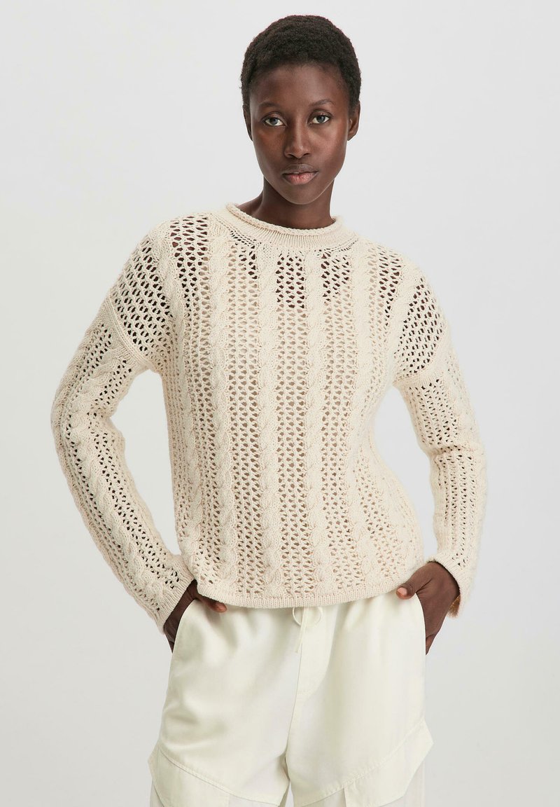 Strickpullover in hellbeige mit Lochmuster, Rundhals und langen Ärmeln, ausgestattet mit einem strukturierten Design und Kabelstrick-Akzenten.