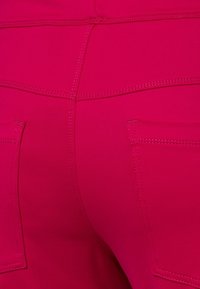 Fuchsia stretchstof broek met een gladde textuur, gebogen naden en twee achterzakken met gestikte details.