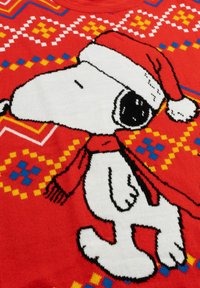 Pullover rosso a maglia con un cane dei cartoni animati che indossa un cappello di Babbo Natale e una sciarpa. Motivi geometrici gialli e blu sullo sfondo.