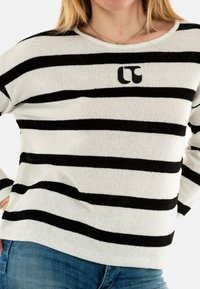 Maglione a righe bianche e nere con vestibilità ampia, scollo rotondo e un piccolo logo sul petto. Tessuto lavorato a maglia con una finitura testurizzata.