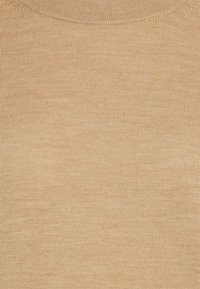 Detailaufnahme eines beigen Strickstoffs mit feiner, gleichmäßiger Rippstruktur und einem dezenten Ausschnitt, der am oberen Rand sichtbar ist.