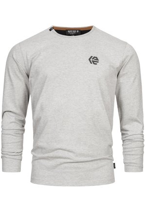 Camisa gris de manga larga hecha de una tela suave, con cuello redondo y un pequeño logo negro en la parte superior izquierda del pecho. Textura suave.