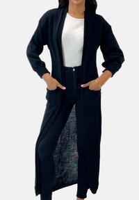 Długi czarny kardigan wykonany z miękkiego materiału dzianinowego. Posiada otwarty przód, dwie kieszenie oraz lekko prążkowane mankiety. Długość do kostek.