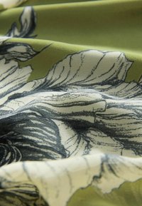 Material floral cu ilustrații de flori alb-negru pe un fundal verde, cu o textură netedă și cute vizibile.