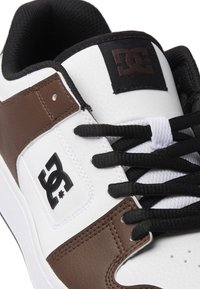 Lightweight sneaker featuring a white and brown leather upper, black mesh tongue, black laces, and a prominent black DC logo.