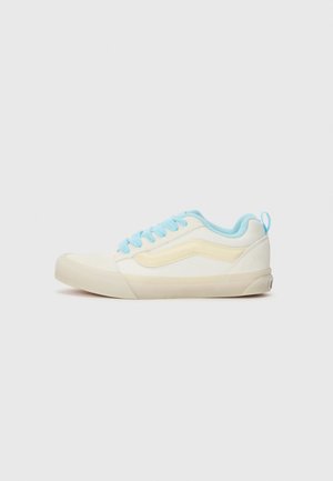 Low-top sneaker in cream and light blue, featuring canvas material, flat laces, retro design, and a textured rubber outsole.