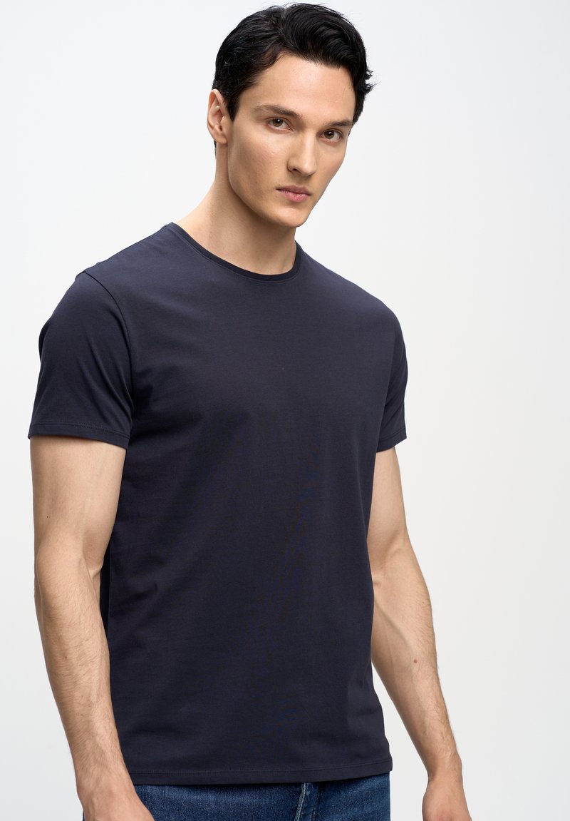 T-shirt blu scuro a maniche corte con scollatura a girocollo, realizzato in morbido cotone. Presenta un design aderente e semplici dettagli di cucitura.