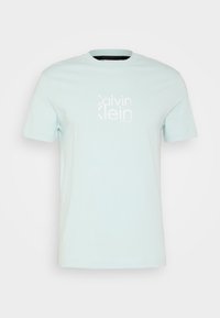 Camiseta de algodón de color azul claro con mangas cortas y cuello redondo. Presenta un logo blanco en la parte frontal. Textura suave, diseño casual.