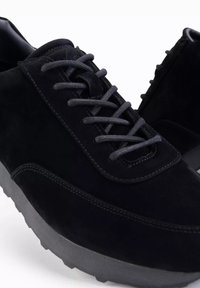 Mustat samettiset kengät, joissa on pyöreä kärki, teksturoitu pinta ja harmaat nauhat, sekä erottuva kumipohja ja huomaamaton ompelu.