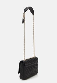 Bolso de mano acolchado negro con forma estructurada, que cuenta con una correa de cadena y un cierre de solapa elegante. Superficie texturizada con patrones ondulados.