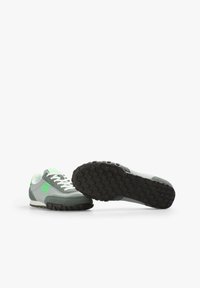 Sneaker mit einem hellgrauen Obermaterial, grünen Akzenten und weißen Schnürsenkeln. Strukturierte schwarze Gummisohle mit kleinen Traktionsstiften. Rundes Zehendesign.