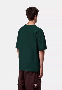 Zielona koszulka z krótkim rękawem o luźnym kroju, wykonana z miękkiej bawełny, z okrągłym dekoltem i raglanowymi rękawami. Bez widocznych wzorów.