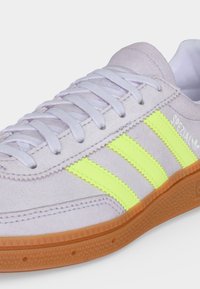 Λευκό αθλητικό παπούτσι Adidas με νέον κίτρινες ρίγες, σόλα από καουτσούκ, λευκά κορδόνια και κείμενο "SPEZIAL" στο πλάι.