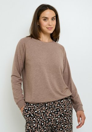 Haut marron à manches longues avec un col arrondi et une coupe décontractée, associé à un pantalon à motif léopard noir et marron. Texture de tissu douce.