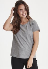 Grå kortærmet t-shirt lavet af blødt stof med en rund halsudskæring og en afslappet pasform, parret med sorte bukser.