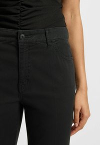 Svarta jeans i slät bomull med knappstängning, femficksdesign och subtila sömdetaljer. Har en slim fit och modern siluett.