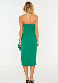 Bandeau grön midiklänning med en åtsittande design, slät textur och en sidodel med drapering. Dragkedjestängning bak.