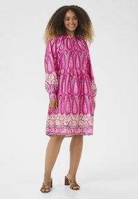 Roza obleka s potiskom z okroglim izrezom, dolgimi napihnjenimi rokavi in zategnjenim pasom. Omenjeni paisley in spirali oblikovani vzorci na svetli podlagi.