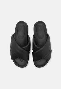 Sandales noires à glissière avec un design croisé. Fabriquées en matériau lisse, dotées d'une semelle intérieure texturée et d'un style ouvert à l'avant.