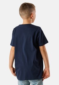 T-paita tummansinistä puuvillaa, jossa on pyöreä kaula-aukko ja lyhyet hihat, yksinkertainen pinta ja rento istuvuus, nähtynä takaa.