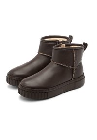 Botas de tobillo de cuero marrón con un acabado texturizado, que presentan una costura trenzada y cierre de cremallera, montadas sobre una suela de goma gruesa.