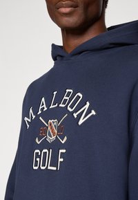 Hoodie bleu marine avec le texte "MALBON" et des broderies sur le thème du golf. Tissu doux avec une coupe décontractée et une capuche réglable à cordon.