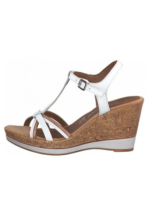 Białe sandały na koturnie z korkową podeszwą środkową, regulowanym paskiem wokół kostki i krzyżującymi się paskami. Gładka faktura cholewki z solidną podstawą i subtelnymi kontrastującymi akcentami.