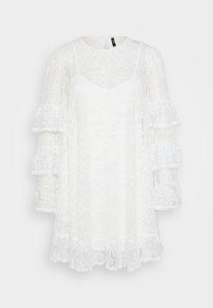 Abito bianco in pizzo con scollatura rotonda, sottogonna a forma di V e maniche lunghe a balze a strati. Tessuto trasparente con motivi floreali su tutta la superficie.