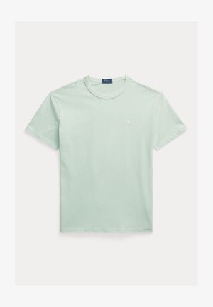 Világoszöld pamutpóló kerek nyakkivágással, rövid ujjú, és a mellkason kis fehér logóval. Sima textúrájú és egyszerű kialakítású.