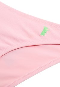 Tissu rose à la texture douce, orné d'un motif d'animal brodé en vert. Le bord présente des détails de pointure soignés.