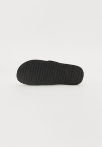 Talpa de sandală din cauciuc negru cu design texturat pentru aderență. Prezintă șanțuri și litere în relief pentru tracțiune. Margini netede fără accente suplimentare.