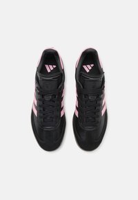 Svarta träningsskor med rosa tre-strips-accenter, med en slät läderöverdel, strukturerad tungad och gummisula.