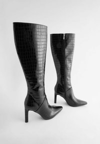Črne čizme do kolen iz sijoče umetne krokodilske kože, z ostrim nosom in peto na stiletto, z dodatkom stranskega zadrge.