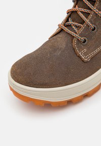 Zapato de senderismo de ante marrón con parte superior texturizada, suela de goma naranja con tacos de tracción y cordones azules y naranjas.