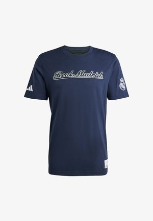 Námornícky modré bavlnené tričko s vyšívaným textom "Real Madrid" v bielej farbe, s bielym logom Adidas na ľavom rukáve a tímovým erbom na pravom.