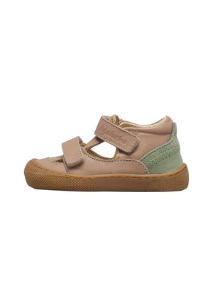 Scarpa beige per bambino con due cinturini in Velcro regolabili, inserto in pelle scamosciata verde sul tallone e suola in gomma marrone con texture.