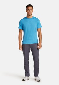 T-shirt azzurro a maniche corte realizzato in tessuto morbido, abbinato a pantaloni grigi scuri con vestibilità slim e dettagli di cucitura discreti.