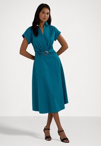 Vestido verde-água com mangas curtas, design envolvente e uma fivela decorativa de prata na cintura. Tecido suave, saia até ao joelho e forma em A.