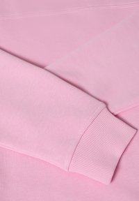 Lichtroze sweatshirt met ribgebreide manchetten. Zachte stoftextuur, met een eenvoudig ontwerp en naadloze constructie in een oversized vorm.