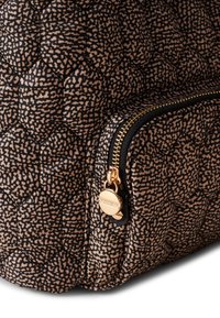 Quilted Stoffhandtasche in Schwarz und Beige, mit einem goldenen Reißverschluss und runden Hardwaredetails, sowie einem strukturierten geometrischen Muster.