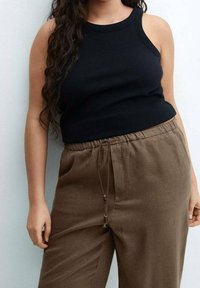 Débardeur noir côtelé associé à un pantalon marron à cordon de serrage. Le tissu semble doux, avec une coupe décontractée et des poches latérales.