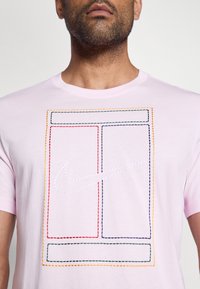 Απαλό ροζ βαμβακερό μπλουζάκι με γραφικό σχέδιο που απεικονίζει περιγραμμένα ορθογώνια σε κόκκινο, πράσινο, κίτρινο και ναυτικό μπλε, καθώς και λευκό λογότυπο της Nike.