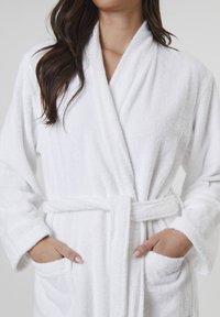 Hvid frotté badekåbe med lange ærmer, omslag design, selvbinder bælte og sidelommer, der har et tekstureret, blødt materiale.