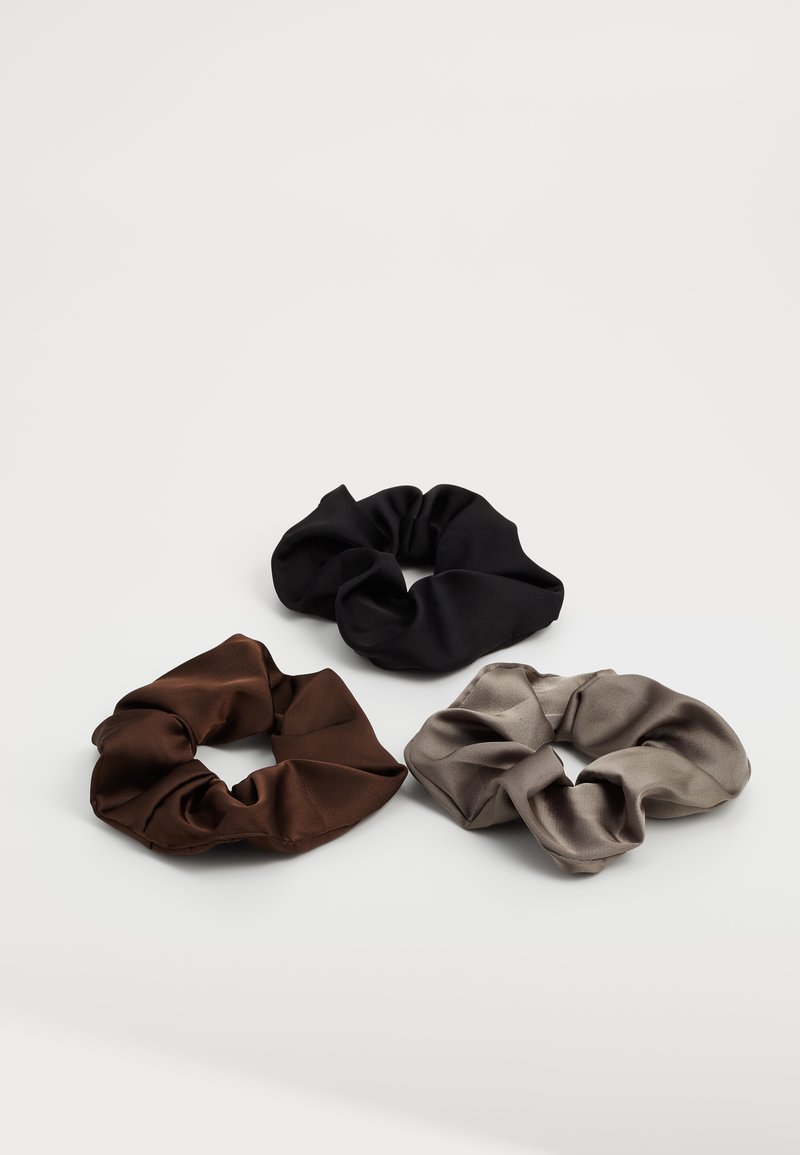 Three satin scrunchies: dark brown, black, and light gray. Each features a soft, smooth texture and a gathered, elasticized design.