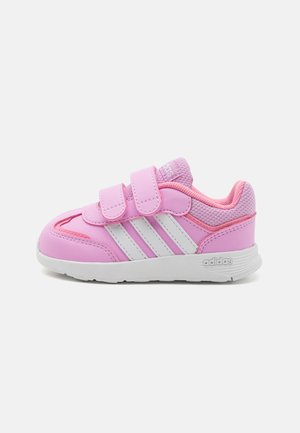 Pantofii sport roz cu dungi albe, prevăzuți cu benzi Velcro, un superior texturat și un guler amortizat. Talpă din cauciuc pentru aderență.