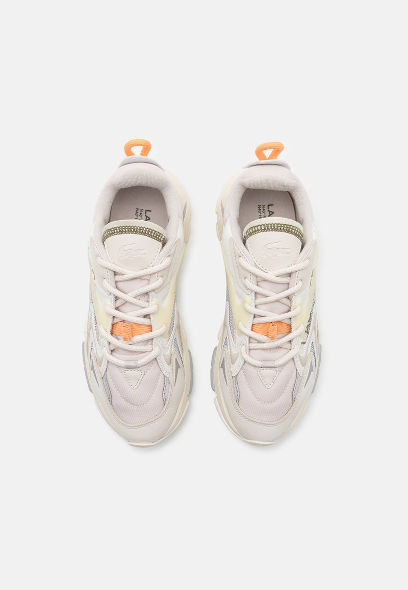 Zapatillas claras de color con materiales de malla y textil. Presentan acentos en naranja y verde, una suela texturizada y un diseño de cordones.