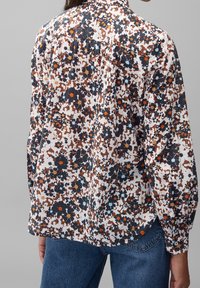 Camicia floreale a maniche lunghe con base bianca e motivi blu navy, arancioni e marroni. Tessuto leggero con vestibilità comoda e polsini con bottone.