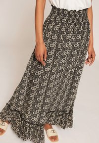 Czarna i biała spódnica maxi z kwiatowym wzorem i falbaną na dole. Elastyczny pas i lekki materiał, z regularnym wzorem małych kwiatuszków.