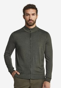 Ciemnozielony kardigan na zamek błyskawiczny z wysokim kołnierzem, prążkowanymi mankietami i gładką teksturą, z centralnym zamkiem i dopasowanym krojem.