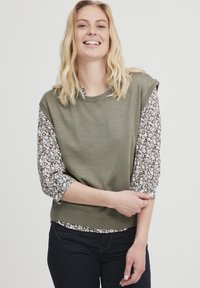 Grøn strikket sweater med kortærmer i blomstermønstret stof. Glat tekstur, ribbet kant og rund hals.